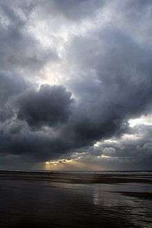 Dark and stormy clouds with sunlight breaking through in the background