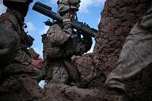 soldiers beside a mud wall