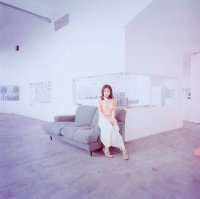 A picture of Utada Hikaru sitting in a greyish living room.