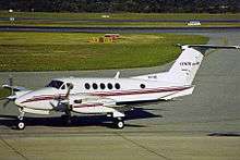 A small aircraft with two propeller engines and six cabin windows on the ground