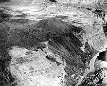 Dark-colored mass of rock draped over the side of a canyon