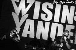 Wisin & Yandel, performing in front of a large sign with their names