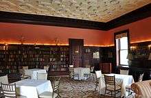 A bookshelf-lined library, with arranged tables and chairs