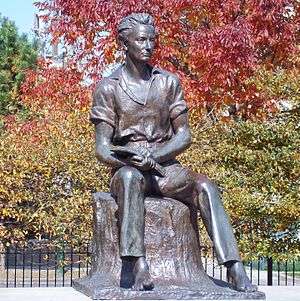 A statue of young Lincoln sitting on a stump, holding a book open on his lap